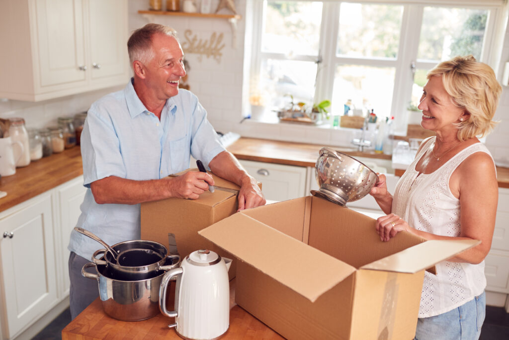 Senior couple labeling a moving box while downsizing their home